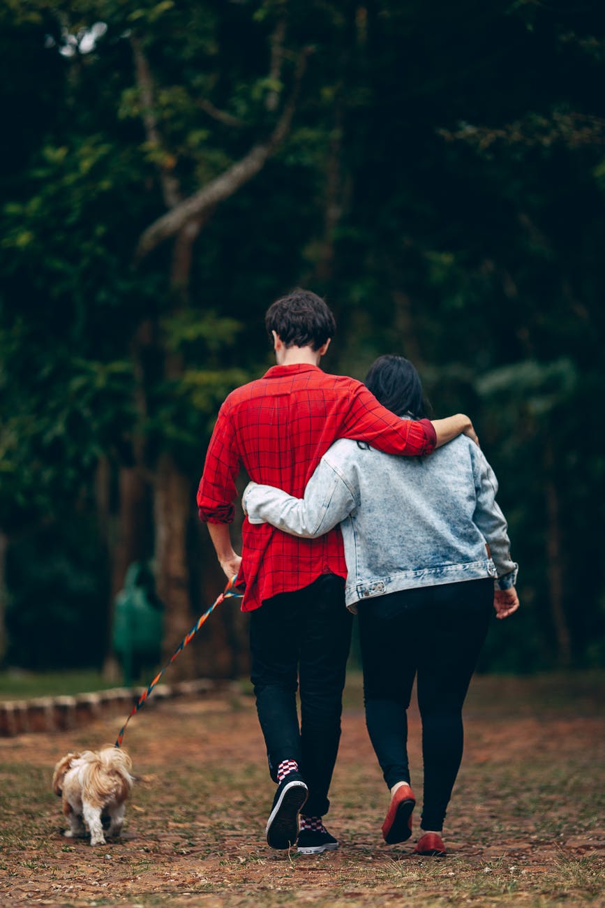 man and woman holding each other walking with dog