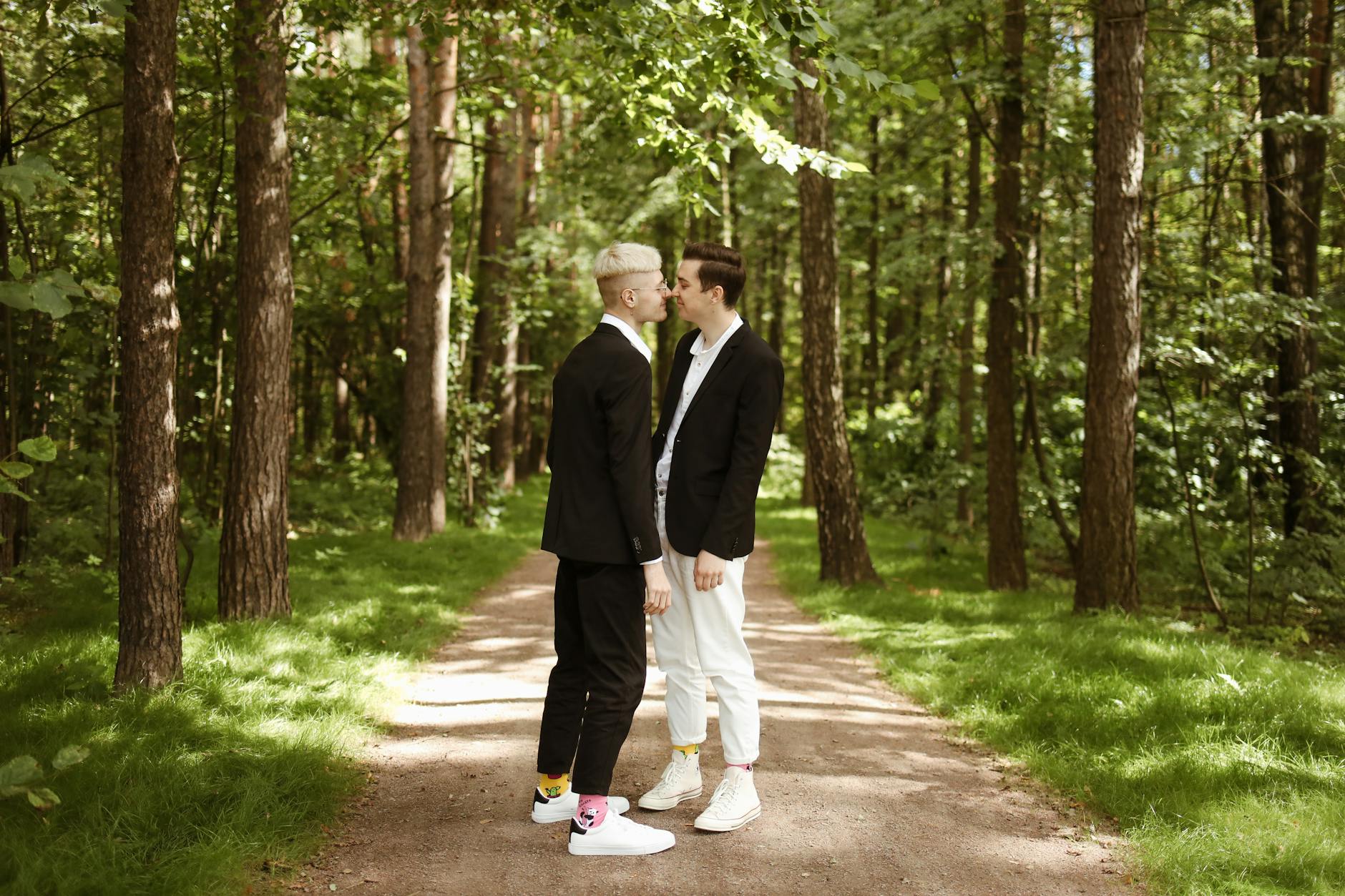 boyfriends nuzzling noses standing on forest path
