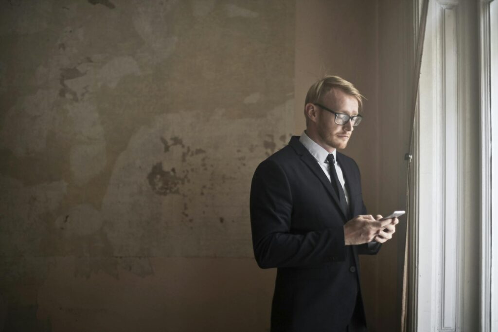 calm young businessman using smartphone in shabby room