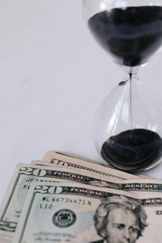 hourglass near pile of american banknotes on table