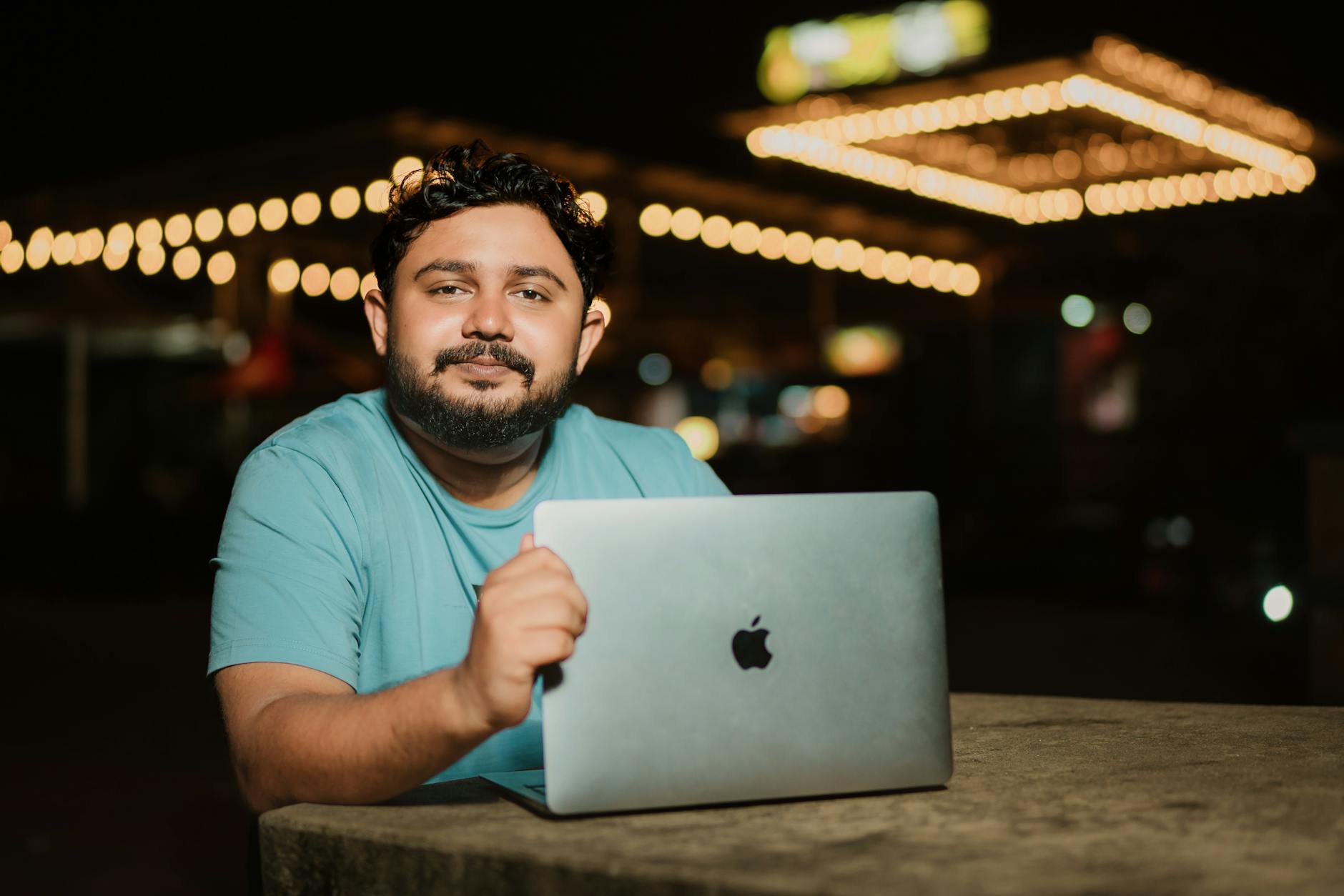 a bearded man sitting at a table with a laptop
