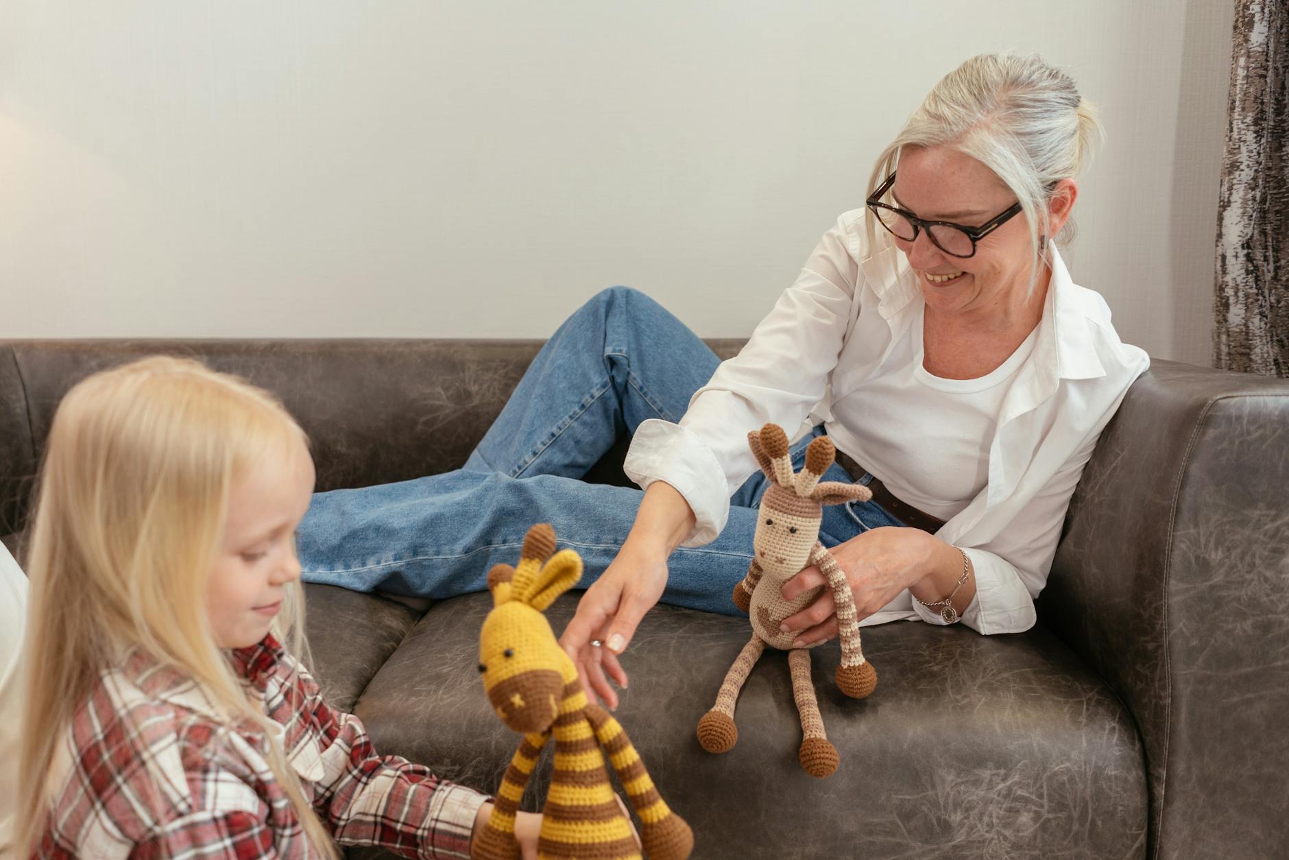 an elderly woman sitting on the couch while playing with her granddaughter