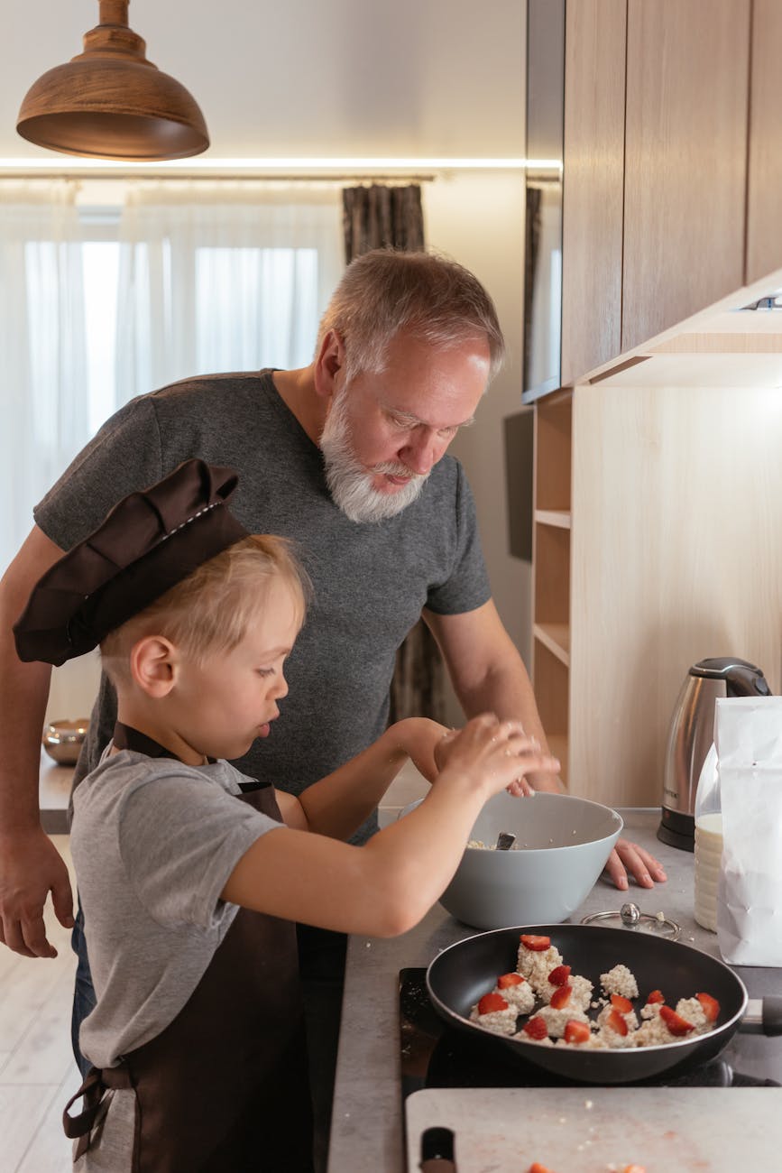 an elderly man talking to his grandchild while preparing food
