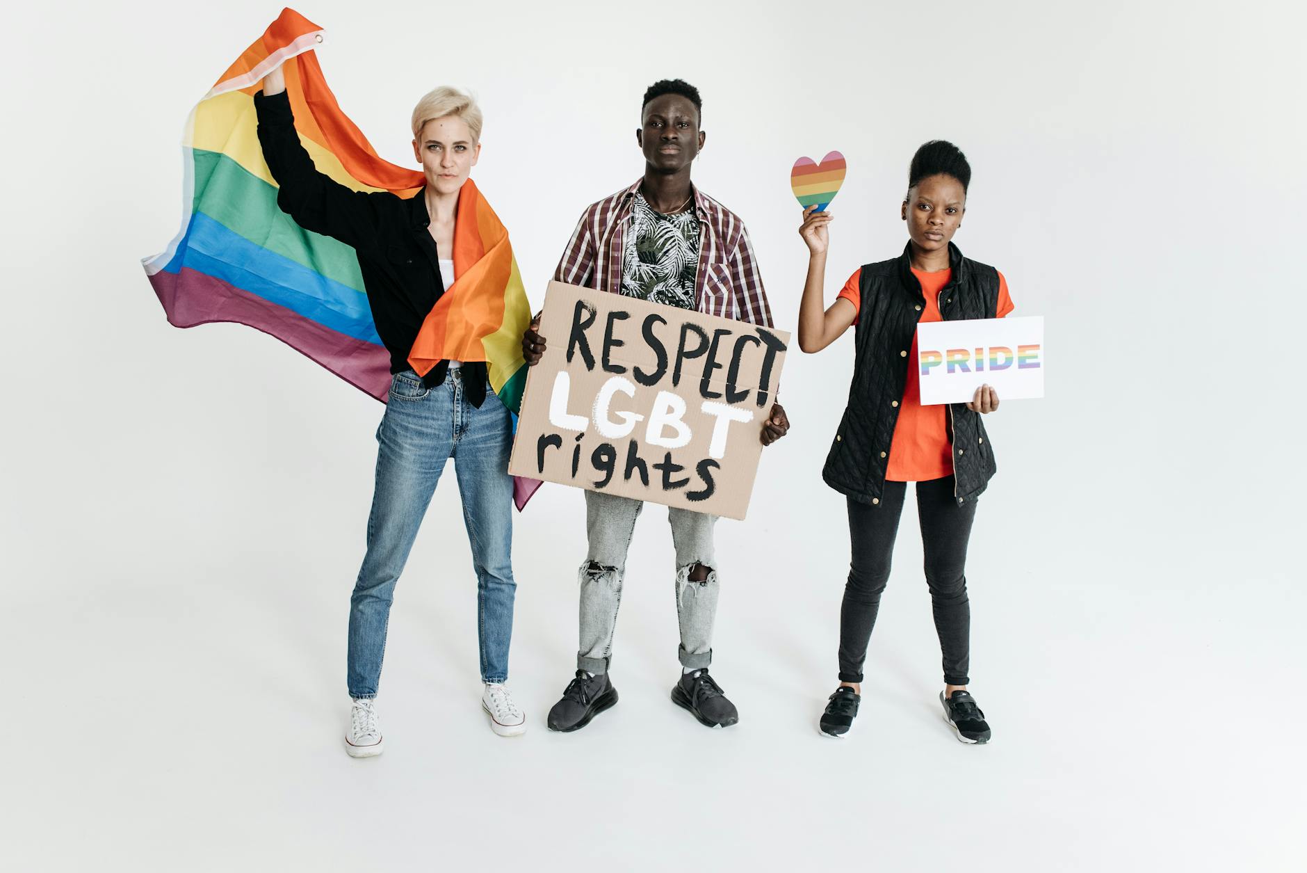 group of people protesting with a rainbow flag and a protest sign